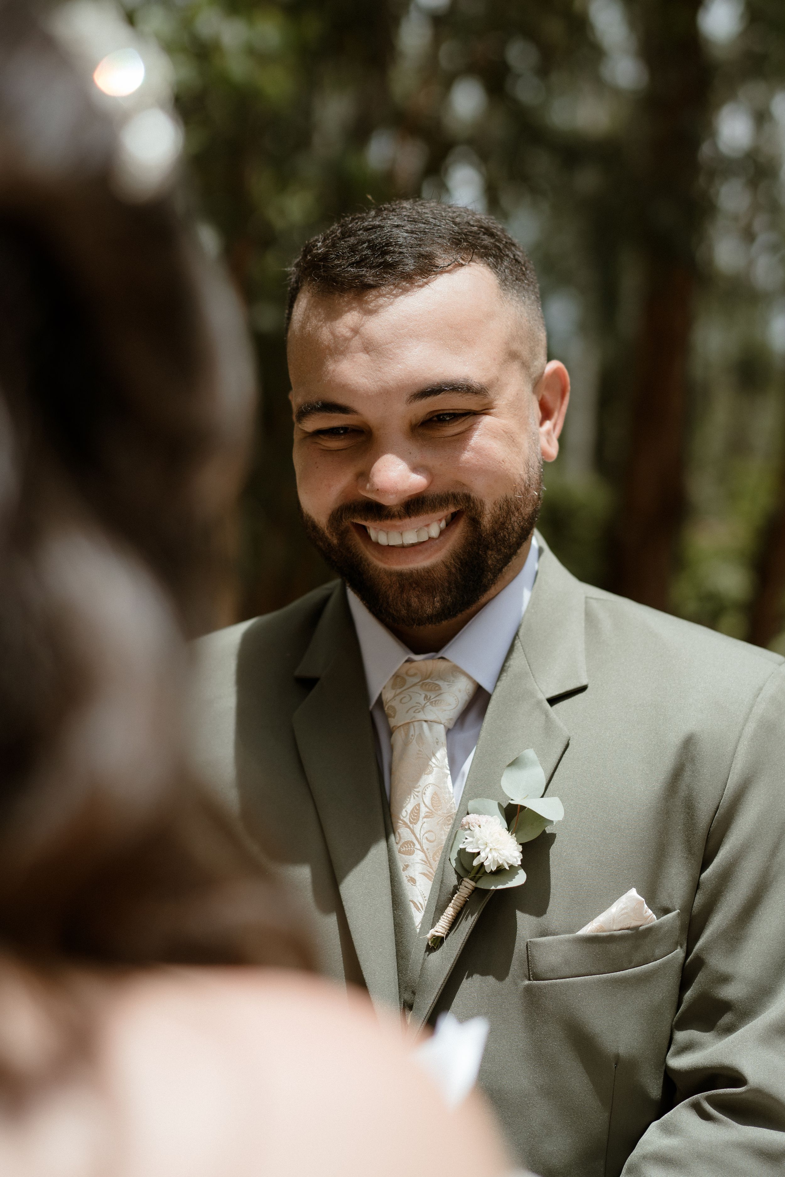 Groom in a sage green suit showing genuine emotion during wedding ceremony.