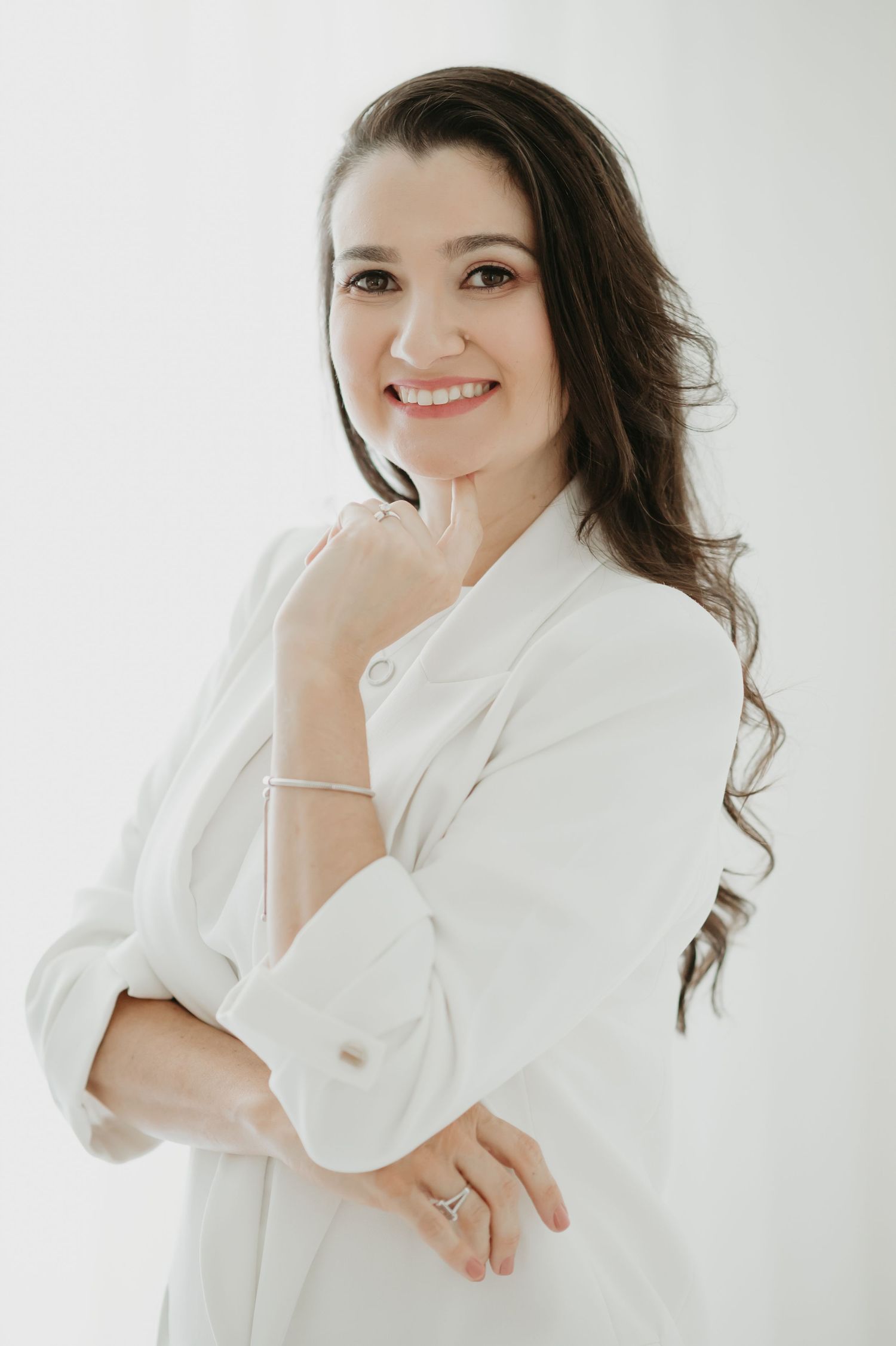 Professional headshot of photographer in white blazer against bright studio background.