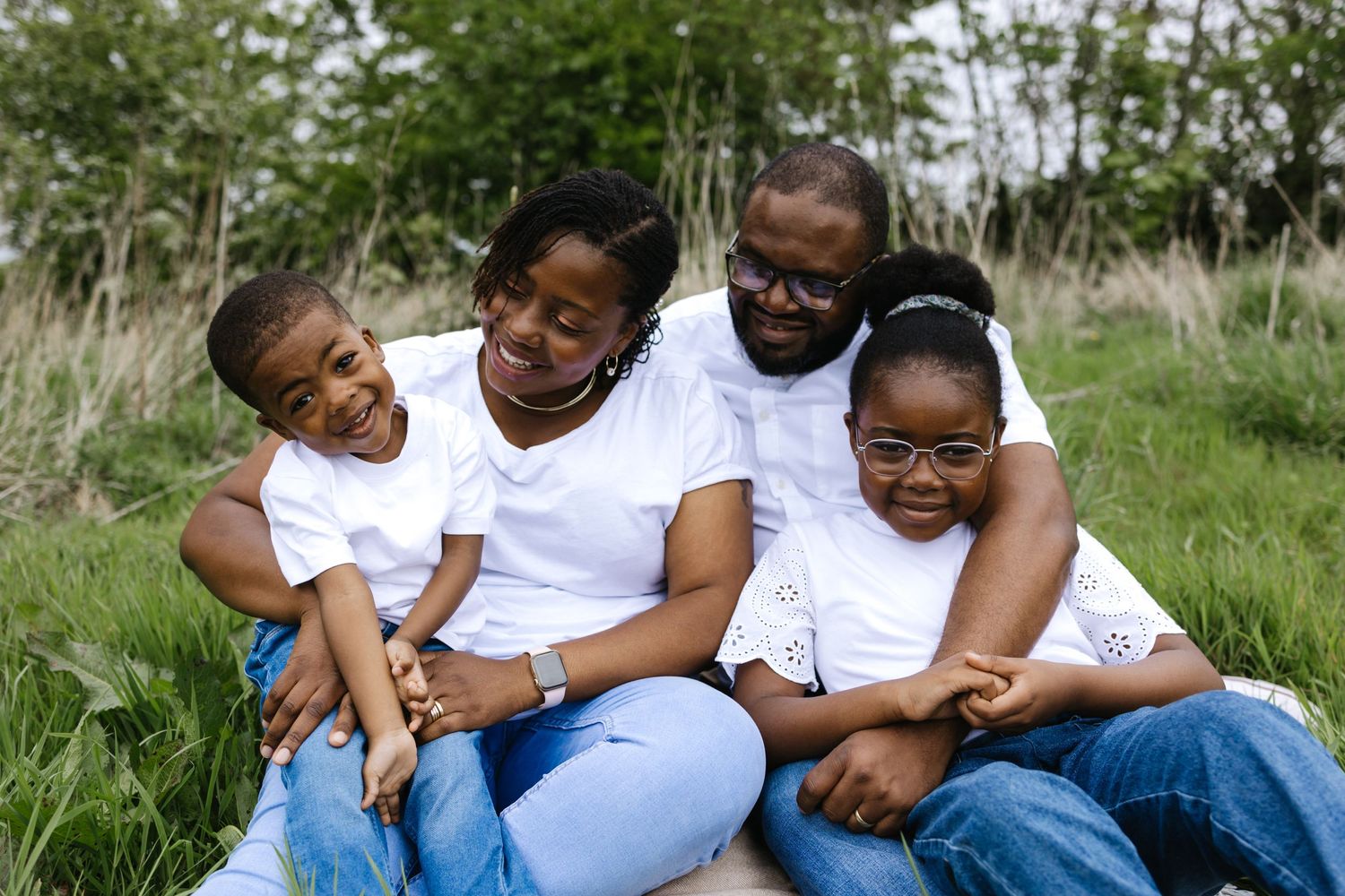 A joyful family wearing matching white shirts relaxing together in a grassy field.