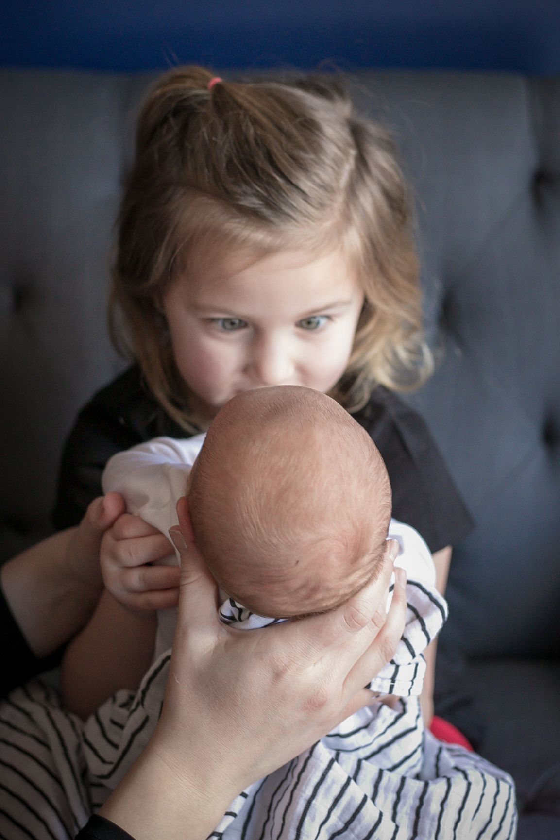 Baby brother being held by his big sister while she talks baby talk to him in Sioux City, IA.