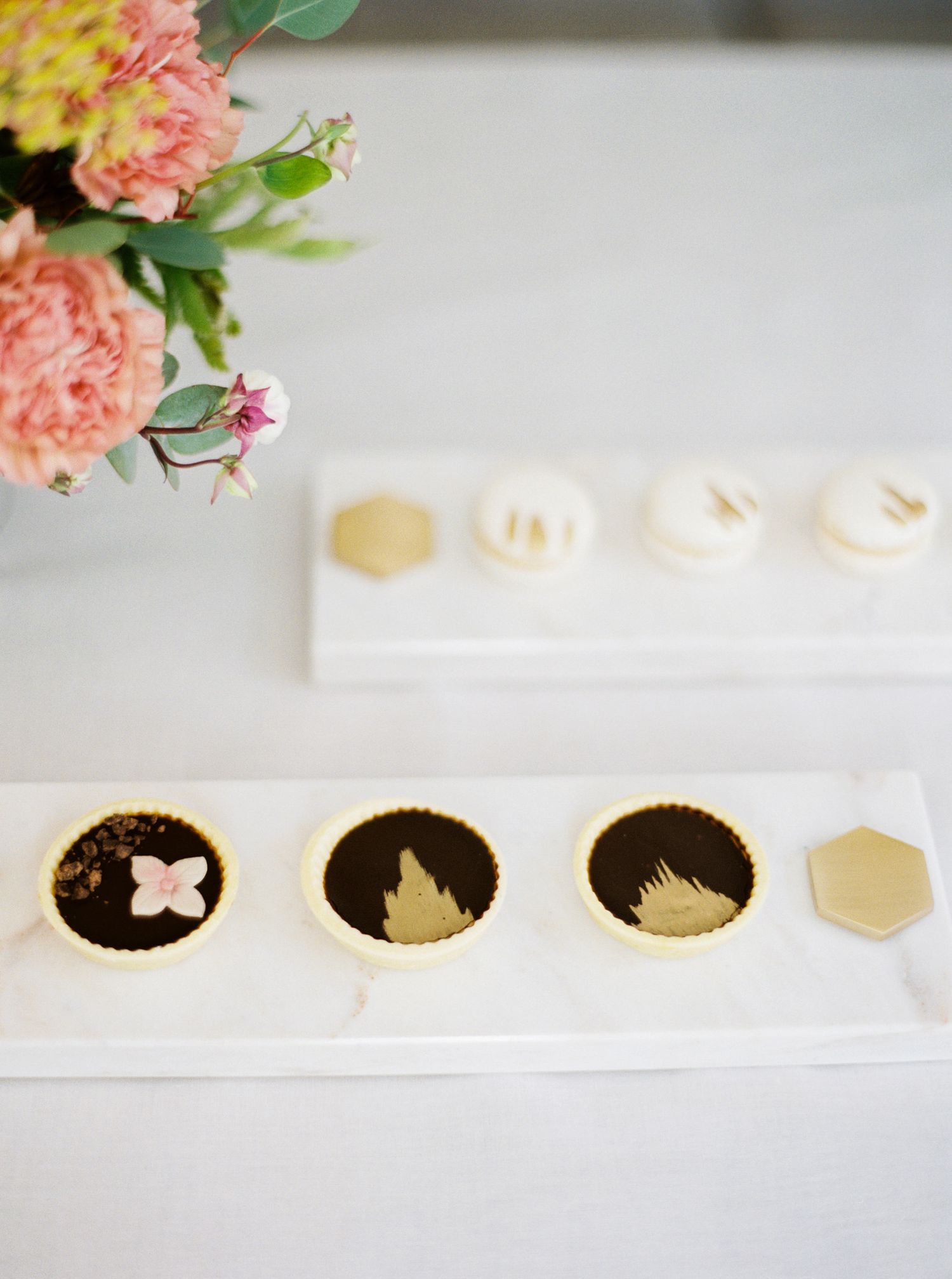Gold macarons on marble platter, elegantly displayed at a wedding reception dessert in Prague.