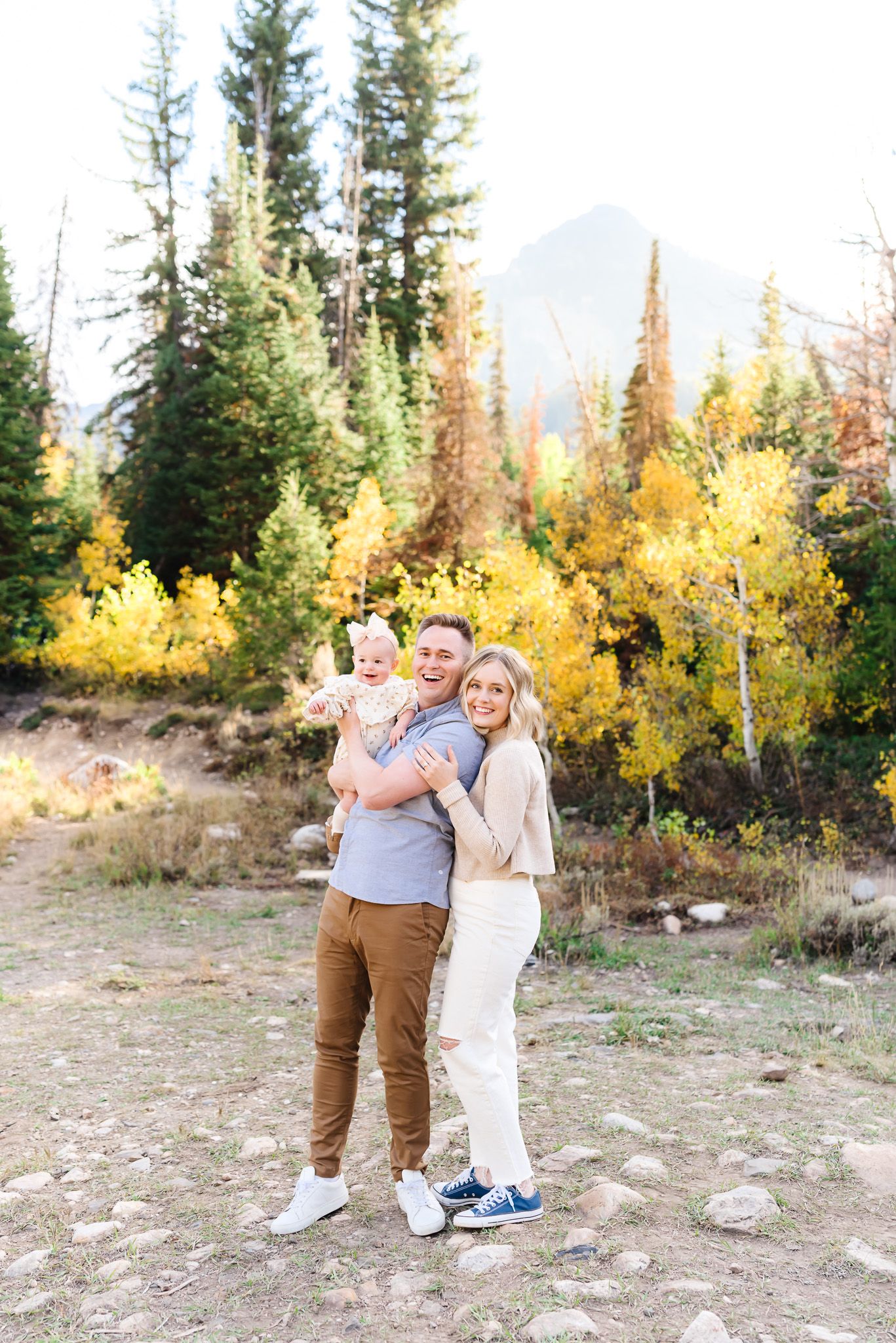 Couple embracing outdoors with golden aspen trees and mountains in the autumn landscape.