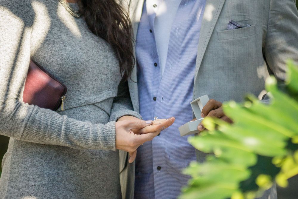 Close-up of hands holding something special between two people in formal attire.