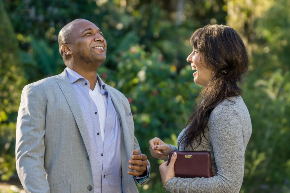 A couple sharing genuine laughter together in a sunlit garden setting.
