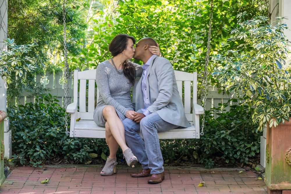 A couple sharing an intimate moment while sitting on a white garden swing.