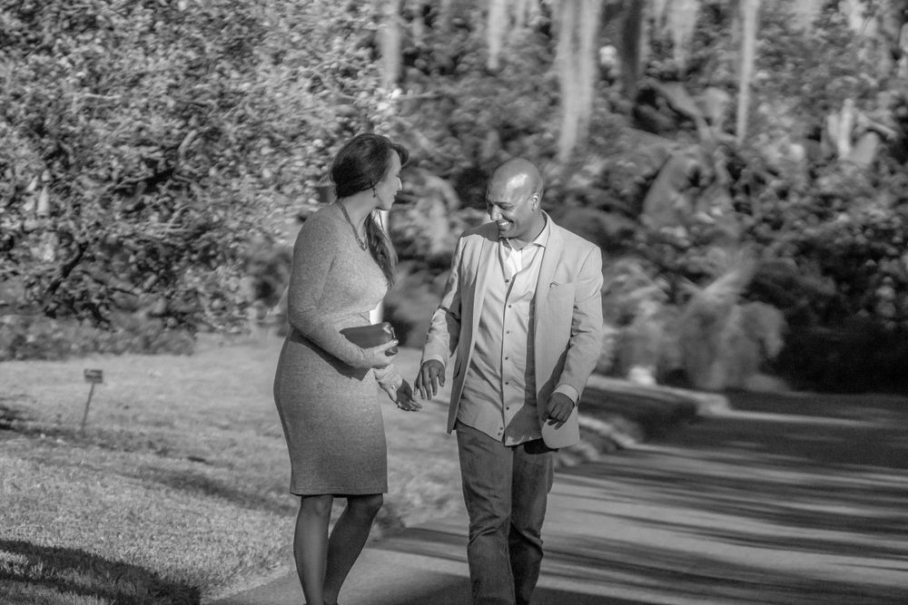 A black and white photo of a couple walking together in a park setting.