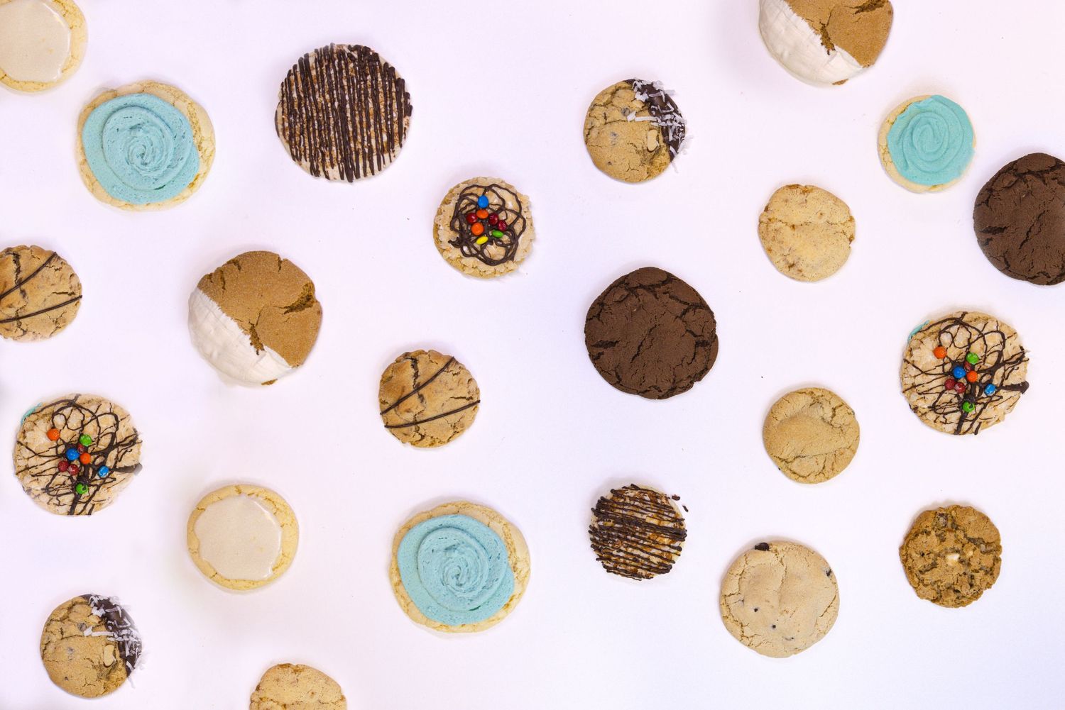 An overhead view of decorative cookies with blue and brown icing arranged on a white background.