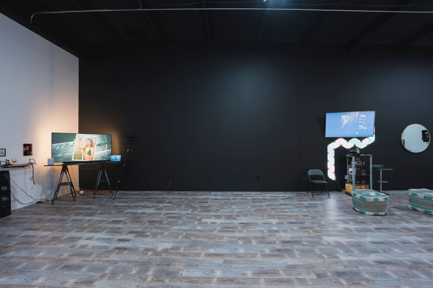 Modern photo studio interior with dark walls, wooden floors, and professional lighting equipment.