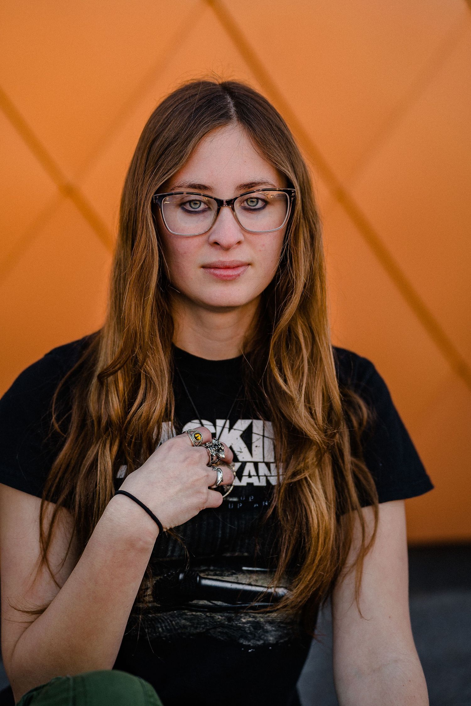 Artistic portrait series with black t-shirt against an orange background.