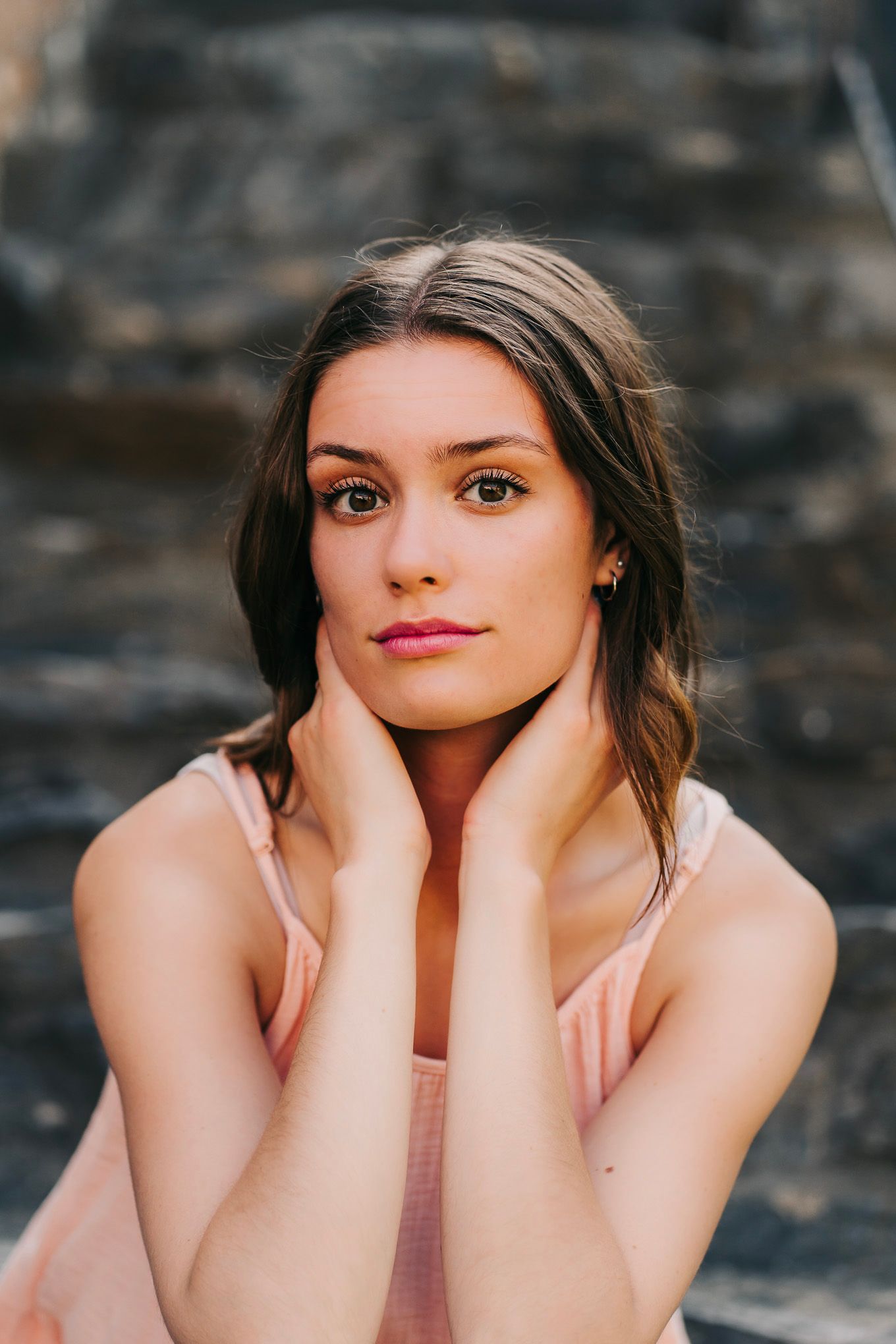 Portrait series with soft lighting against textured stone wall background.