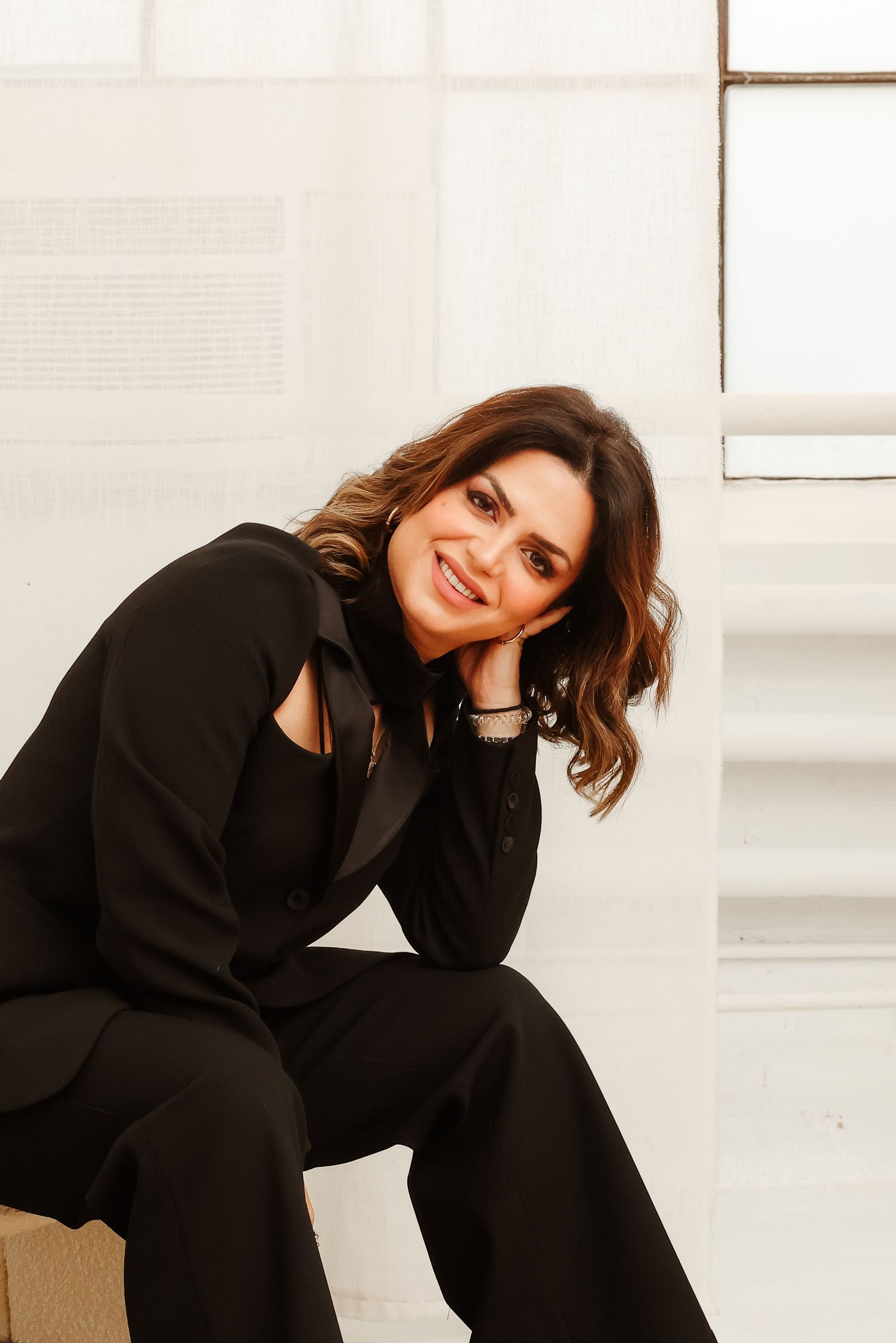 A casual portrait of someone in black clothing sitting and smiling at the camera.