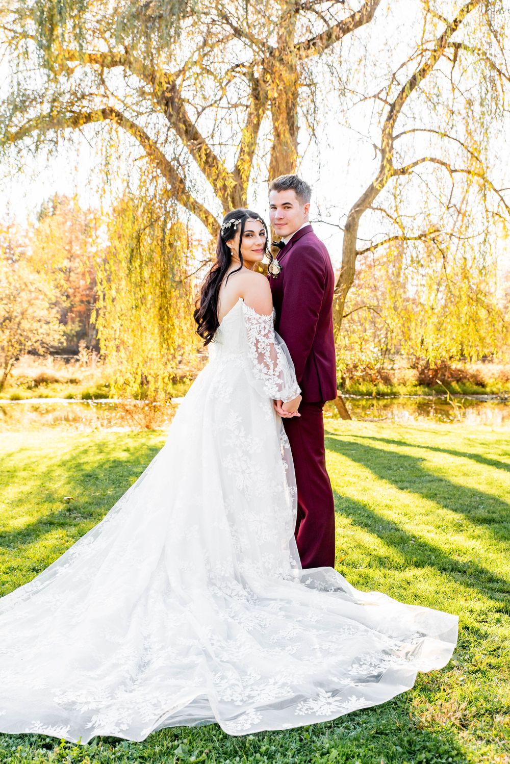 bride and groom on wedding day looking over their shoulders in front of a fall tree pittsburgh pennsylvnia