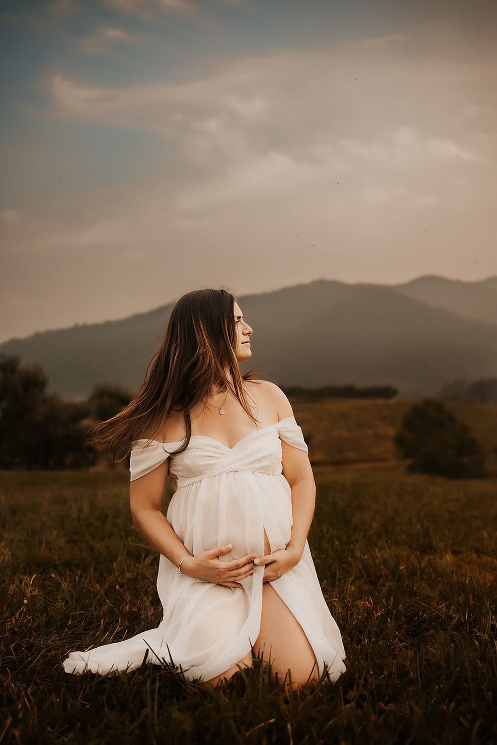 A pregnant mother tosses her hair in the sunshine.