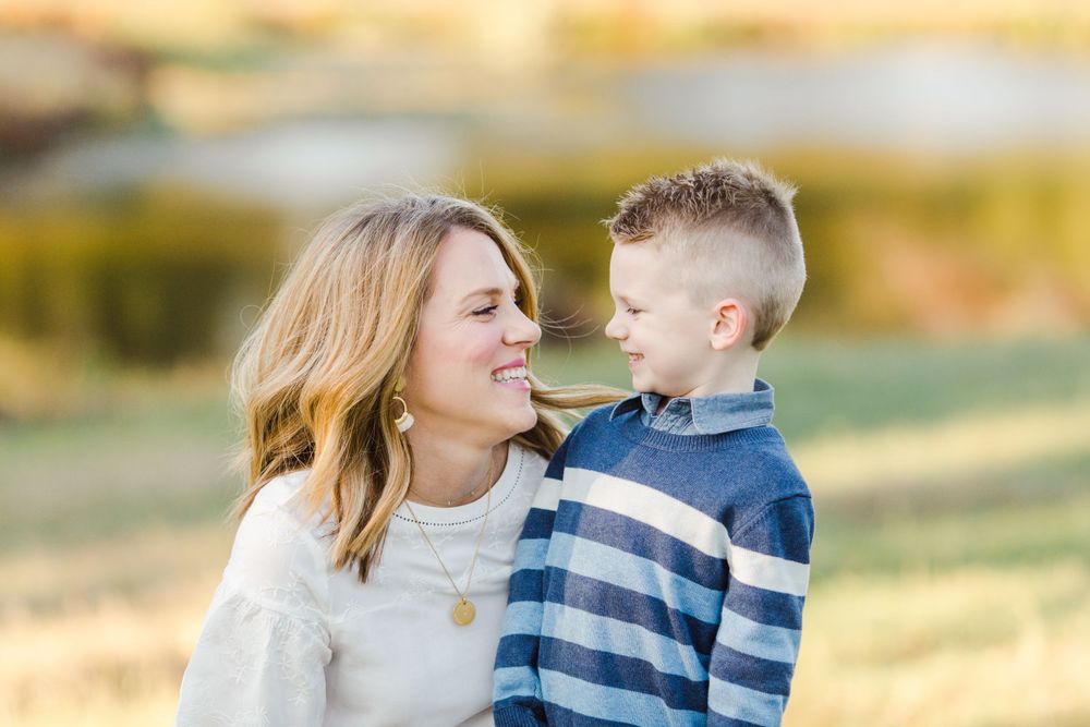 Tender outdoor portrait of a parent and child sharing a joyful moment in warm sunset lighting.