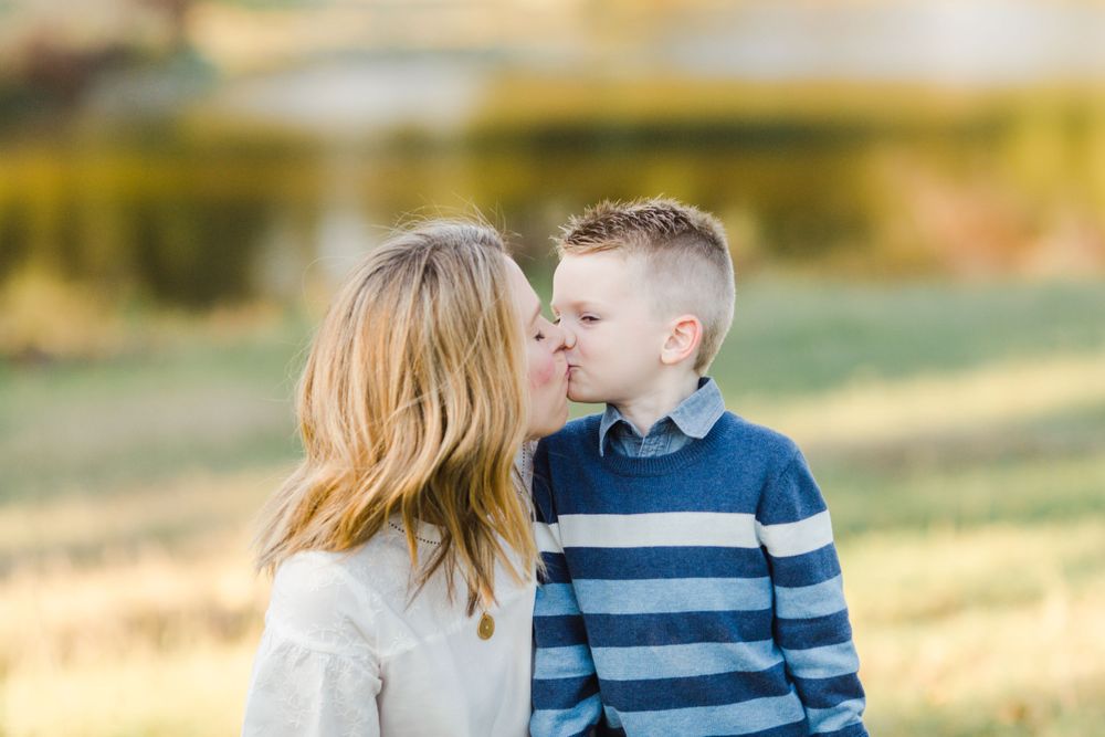 Sweet candid moment between parent and child outdoors in golden hour lighting.