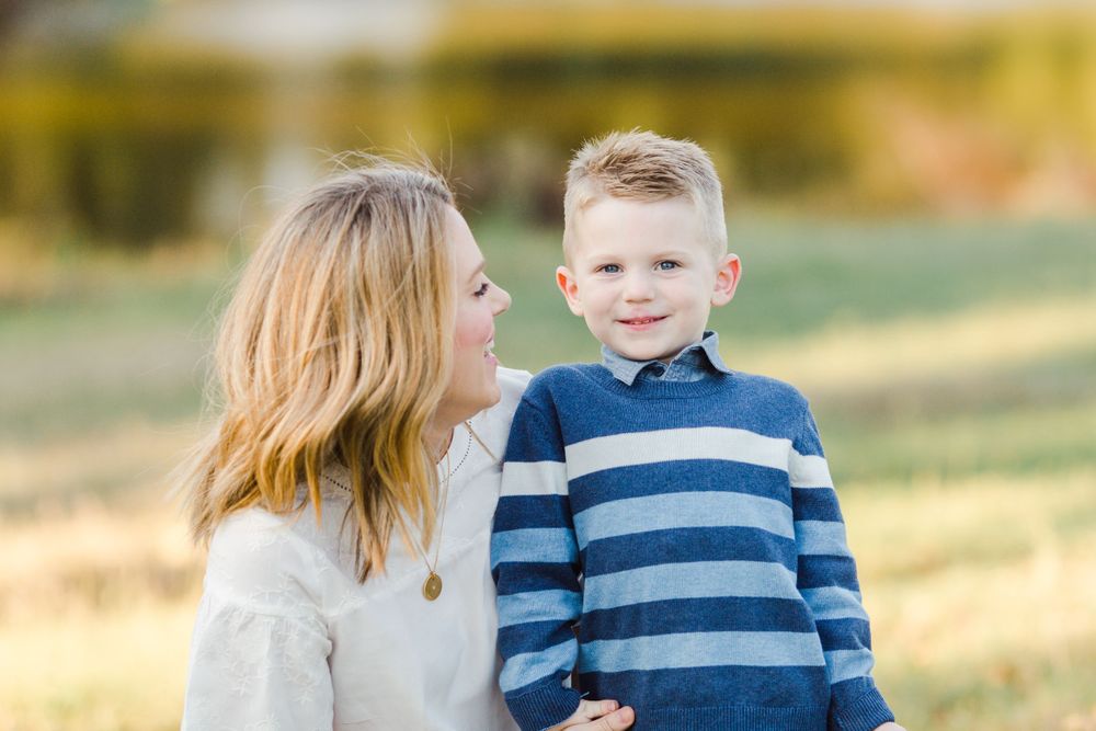 Sweet autumn portrait of a parent and child wearing coordinating blue and white outfits outdoors.