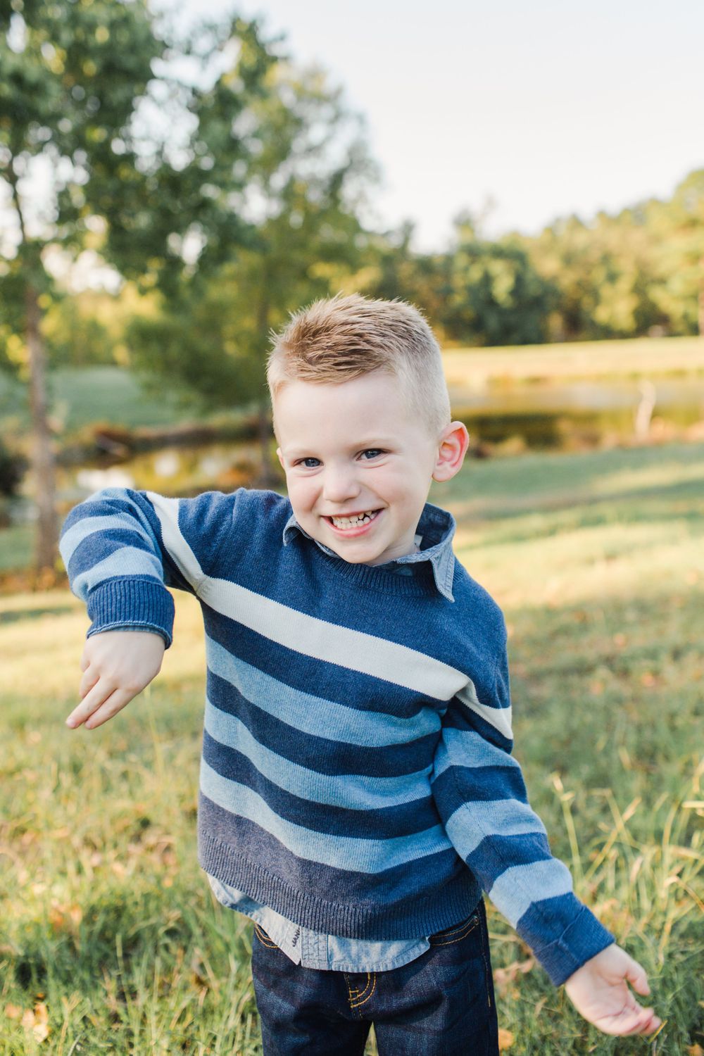 Energetic child in striped sweater playing outdoors in autumn sunlight.