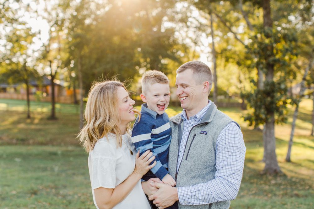 A happy family shares a joyful moment together in a sunny park setting.