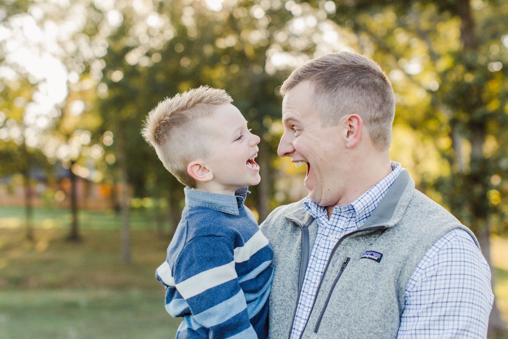 A playful moment shared between parent and child outdoors in autumn.