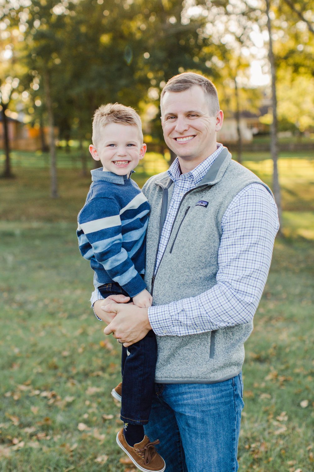 Parent and child share a cheerful moment together in a park during fall.