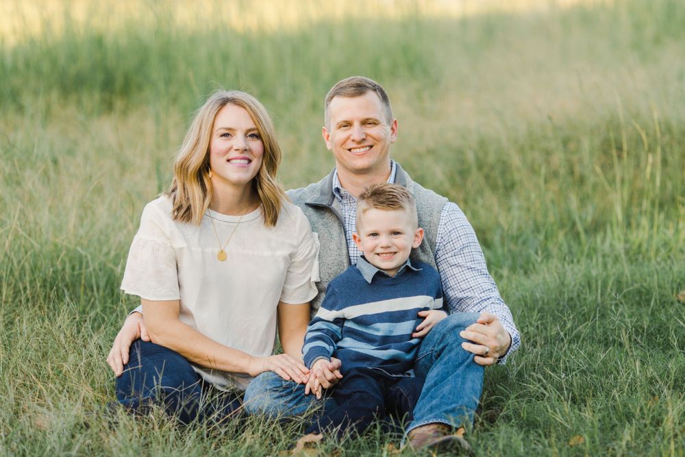Relaxed family portrait taken in a golden field during sunset.