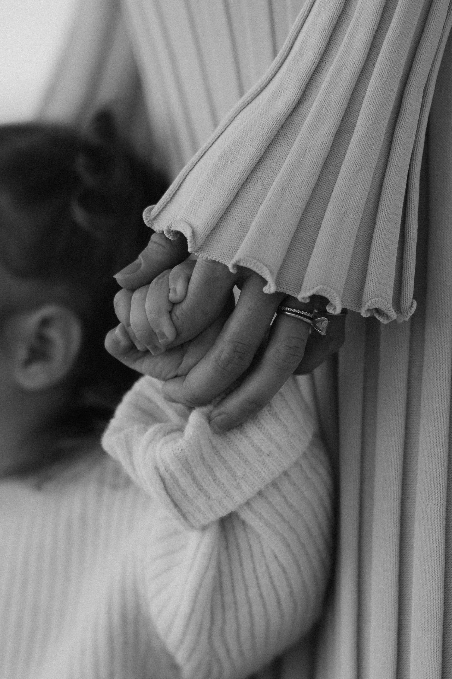 Close-up artistic black and white detail of hands holding delicate pleated fabric.