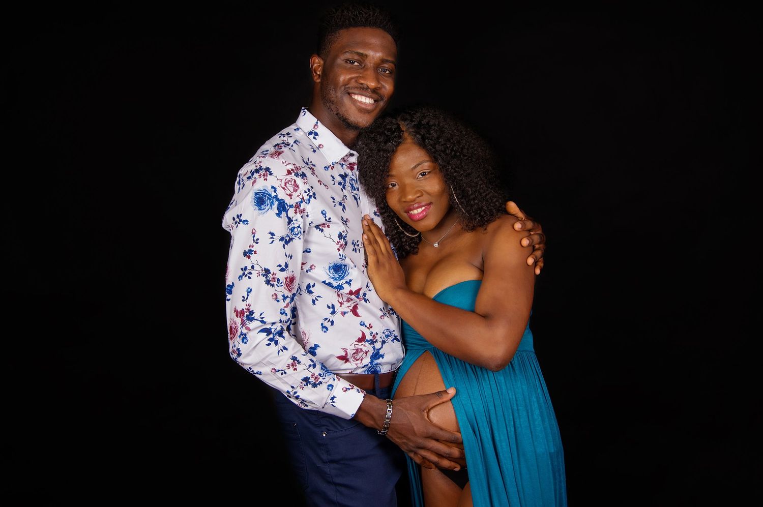 couple in studio posing and embracing pregnant belly