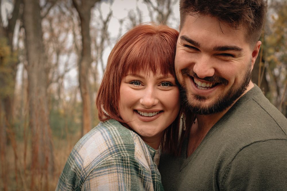 A cozy autumn engagement photo of a couple sharing a tender moment in the woods.