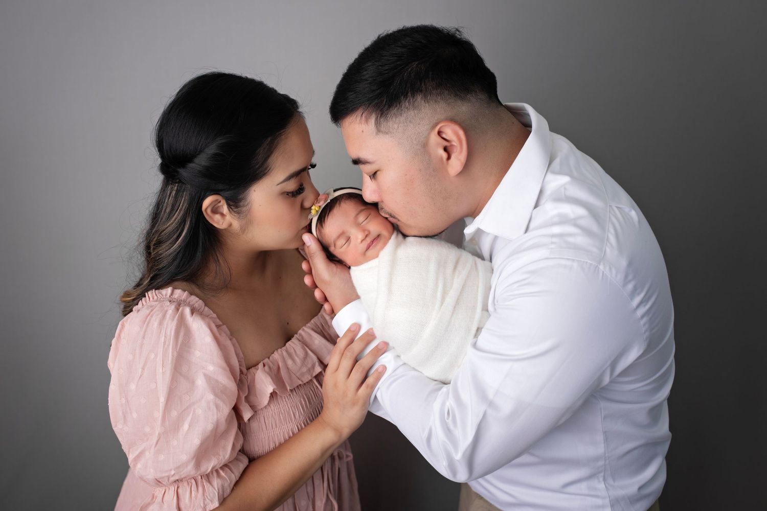 Intimate family portrait with parents sharing joyful moment with newborn.