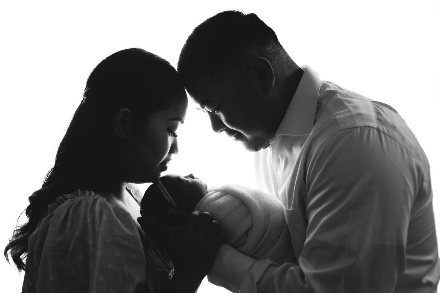 Artistic black and white silhouette of family with newborn.
