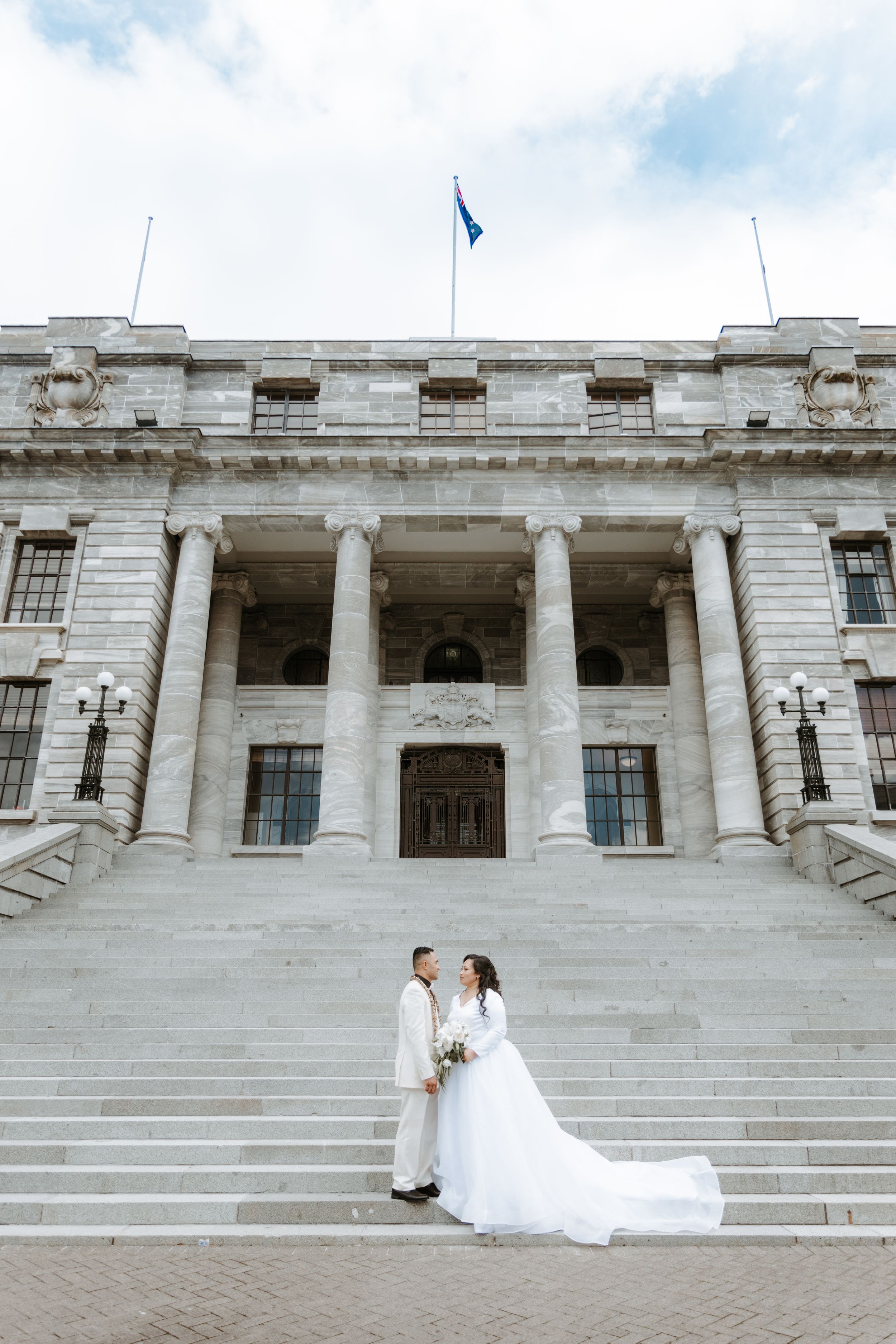 Bride and groom on the steps of New Zealand Parliament - elegant Wellington wedding photography by Selah Weddings.