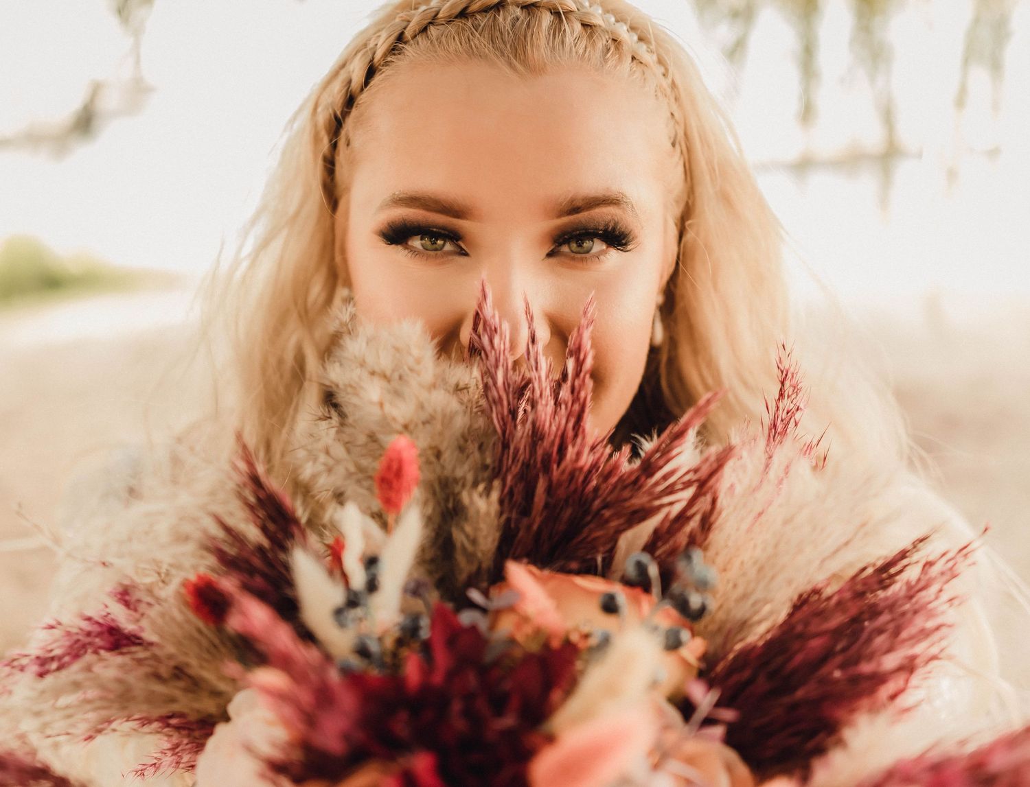 Bride holding a bohemian-style bouquet close to her face, featuring vibrant colors and textures.