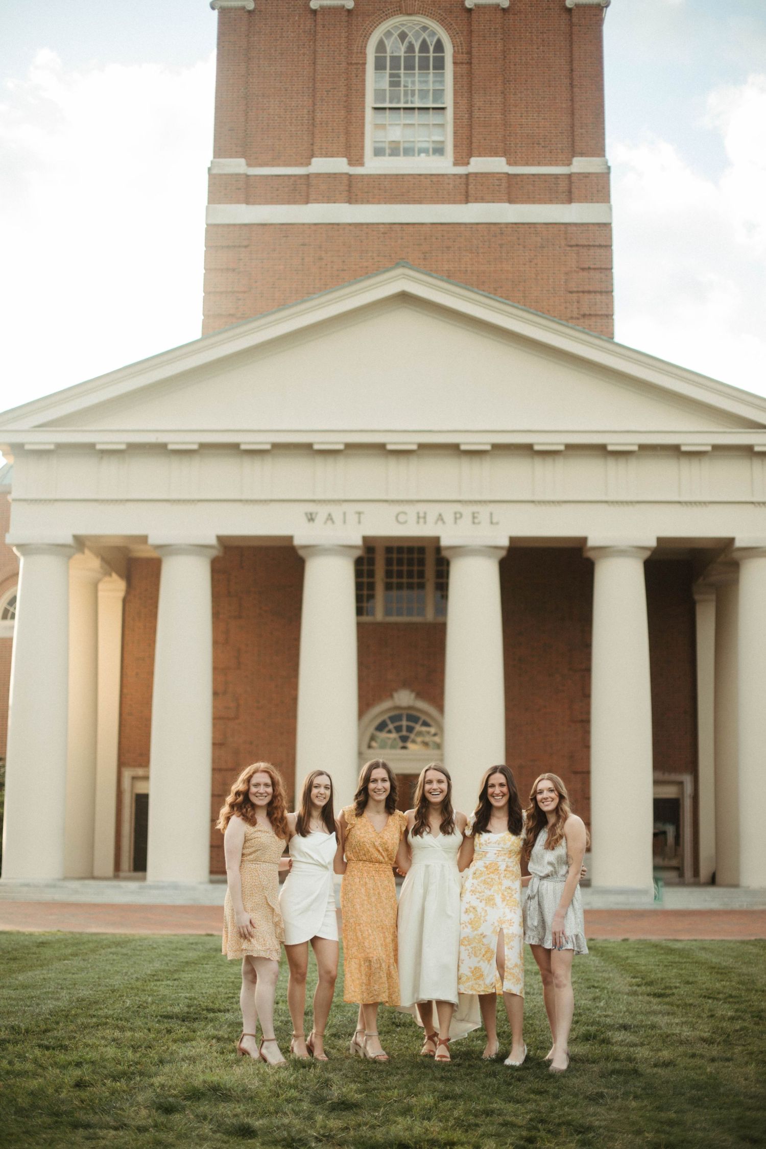 Group photo of friends in pastel dresses standing in front of Wait Chapel's classical columns.