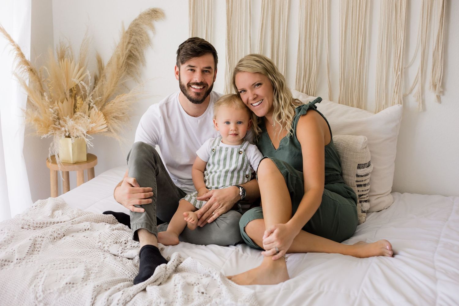 A casual family sitting on the bed and smiling for their lifestyle family portrait session at the studio.