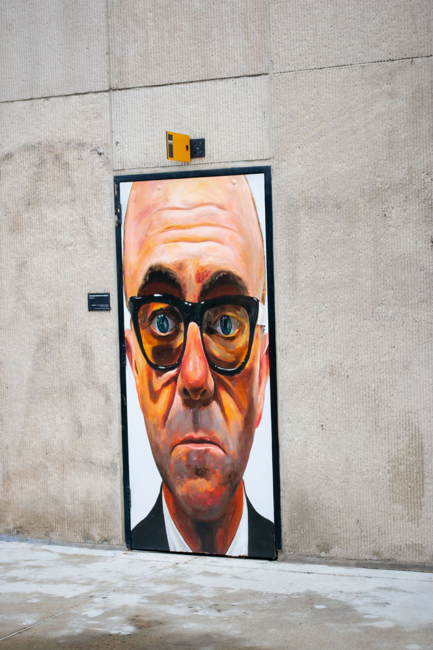 Street art mural of an exaggerated face painted on a concrete wall door.