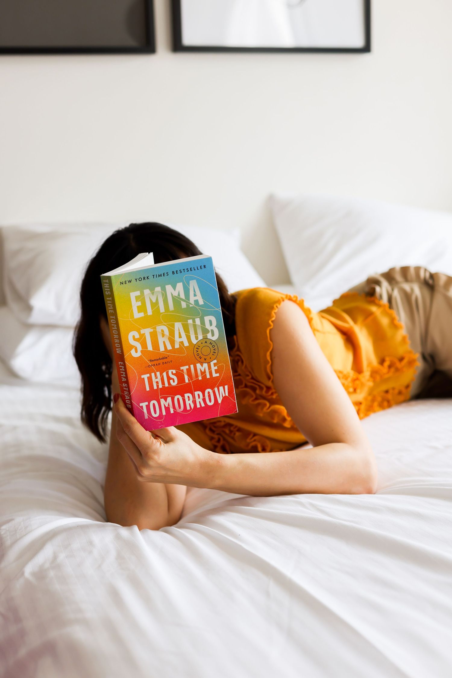 A colorful book about time lies on white bedsheets in warm natural lighting.