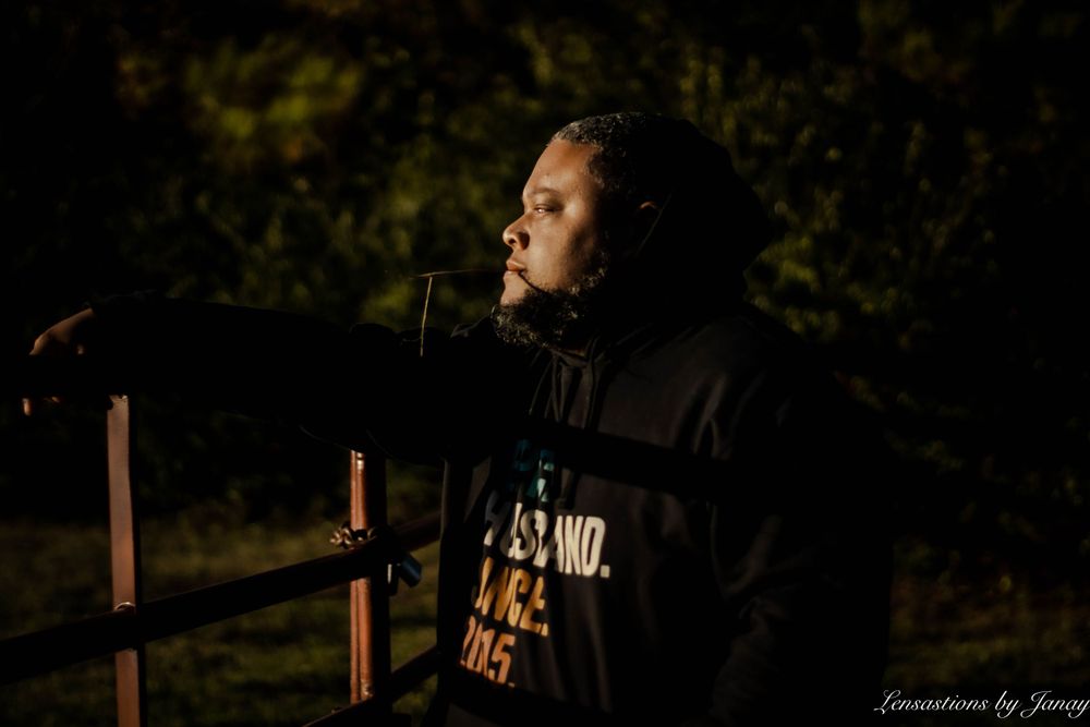 Person in black hoodie speaking at a microphone outdoors at night.