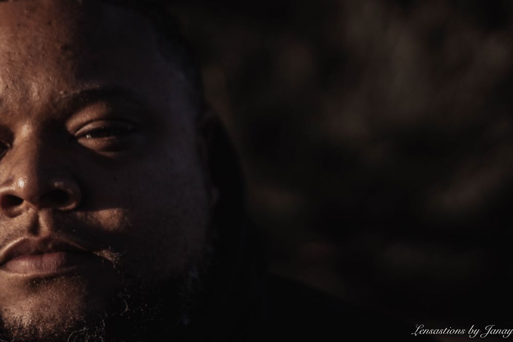 Close-up portrait of a Black man with beard against a dark background.