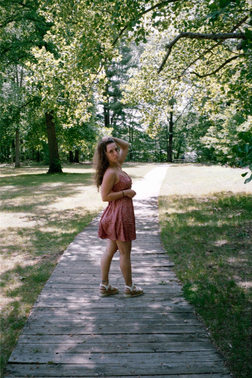 Fashion photography on a wooden boardwalk surrounded by lush summer foliage.