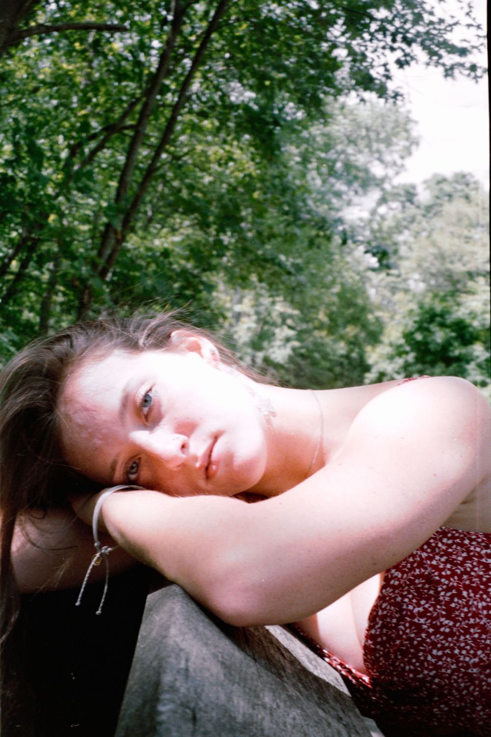 Artistic portrait series taken on a wooden railing in a forest setting.