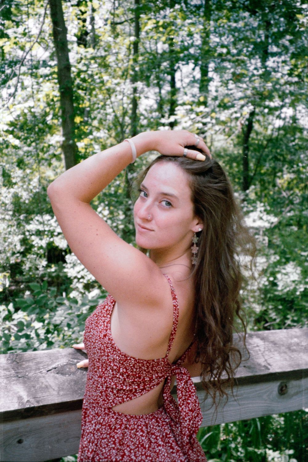 Outdoor photography session featuring red floral dress against natural woodland backdrop.