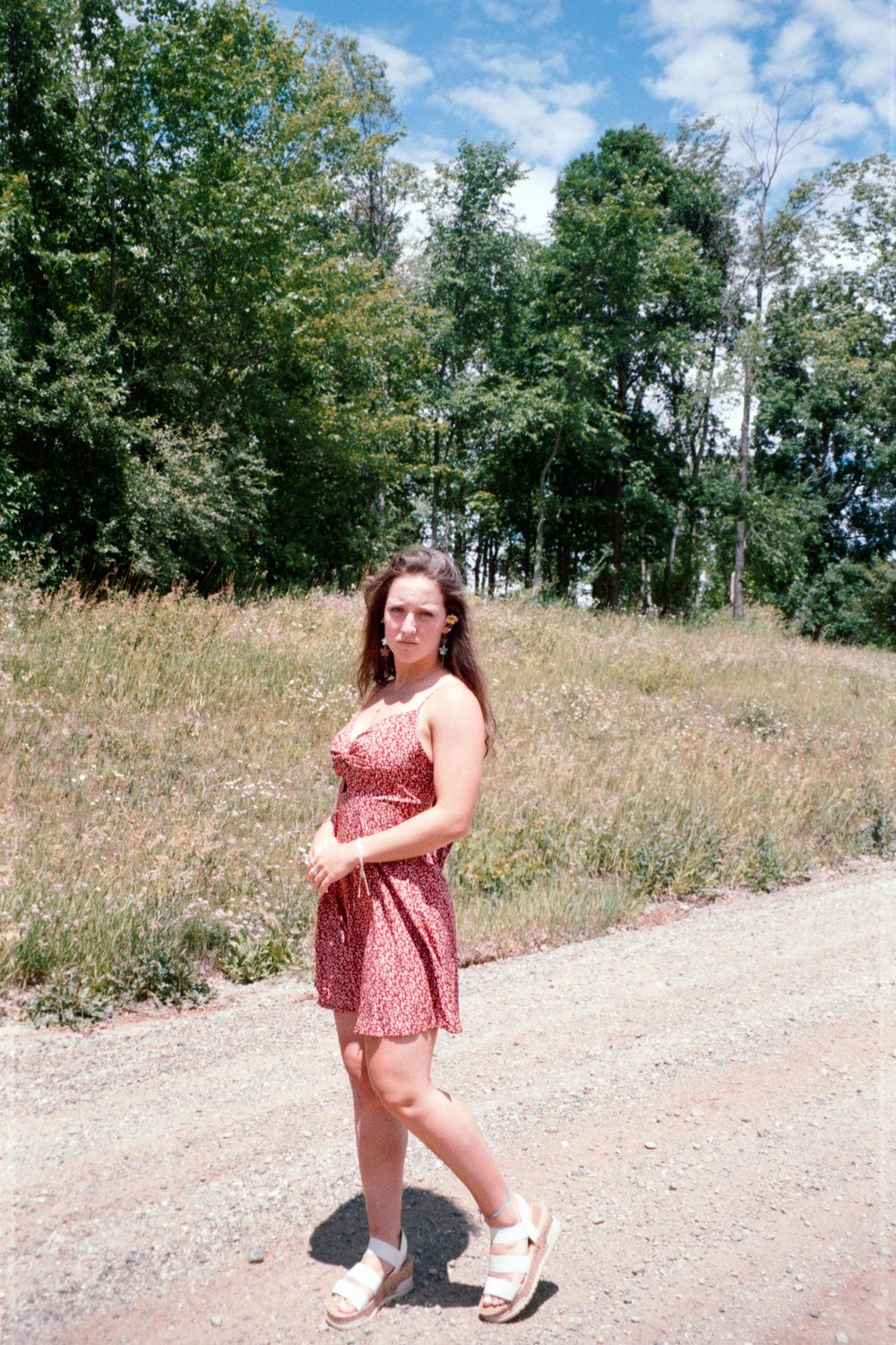 Casual summer photoshoot on a gravel path surrounded by tall grass and trees.