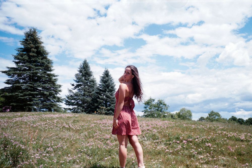 Nature photography session in an open field with evergreen trees in background.
