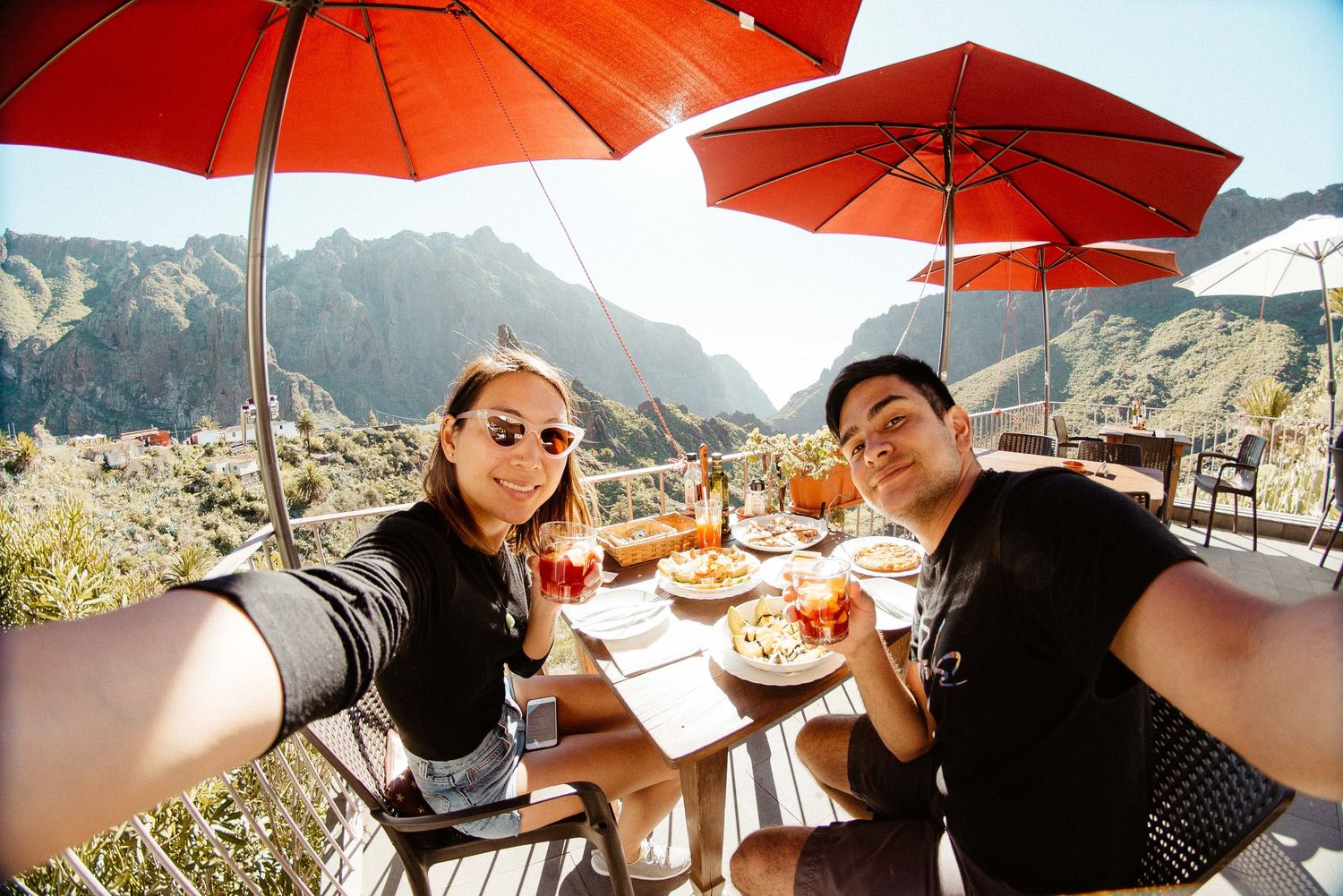 Orange umbrellas providing shade at an outdoor dining area with mountain views.