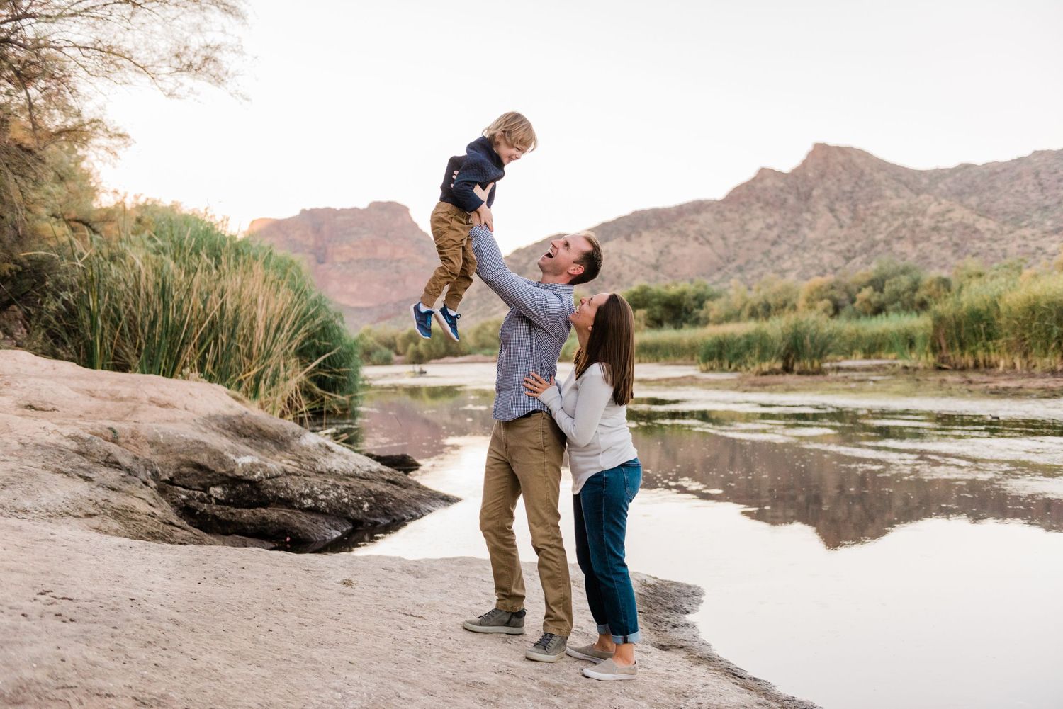 A playful moment captured near a serene water's edge with mountains in the background.