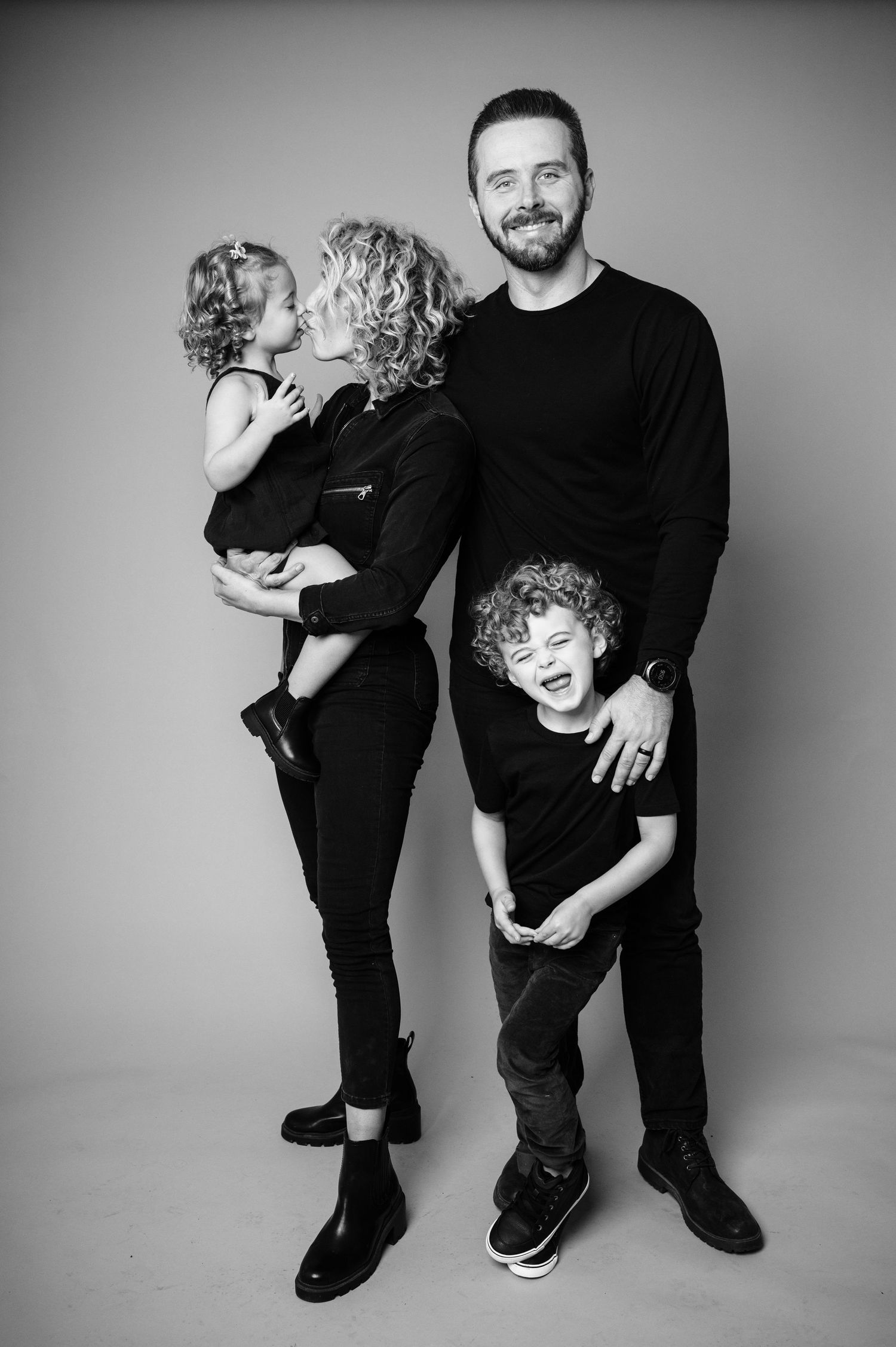 Black and white studio portraits showing playful interaction between two people in dark clothing.