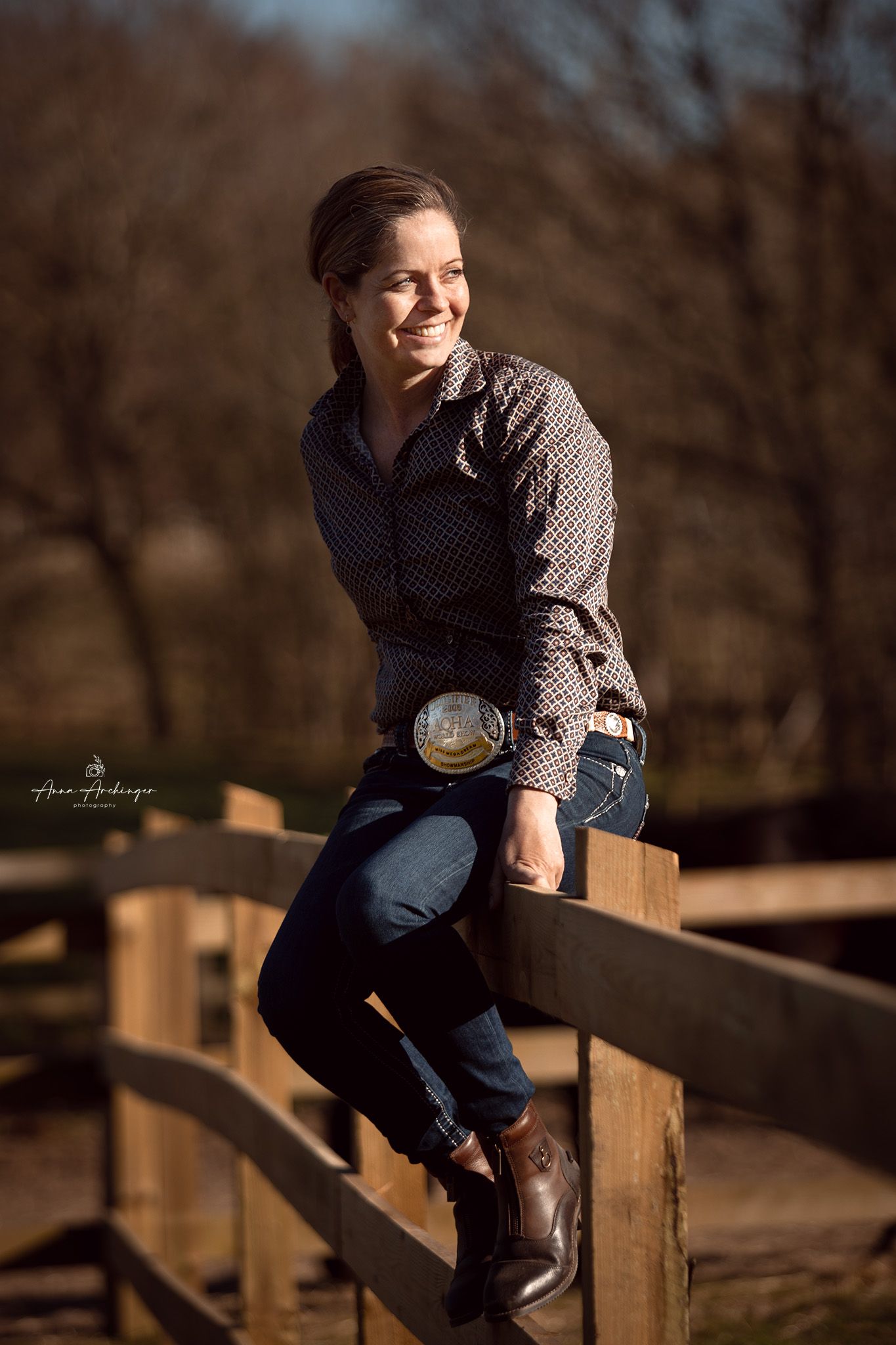 Portrait of someone sitting casually on wooden fence in western attire.