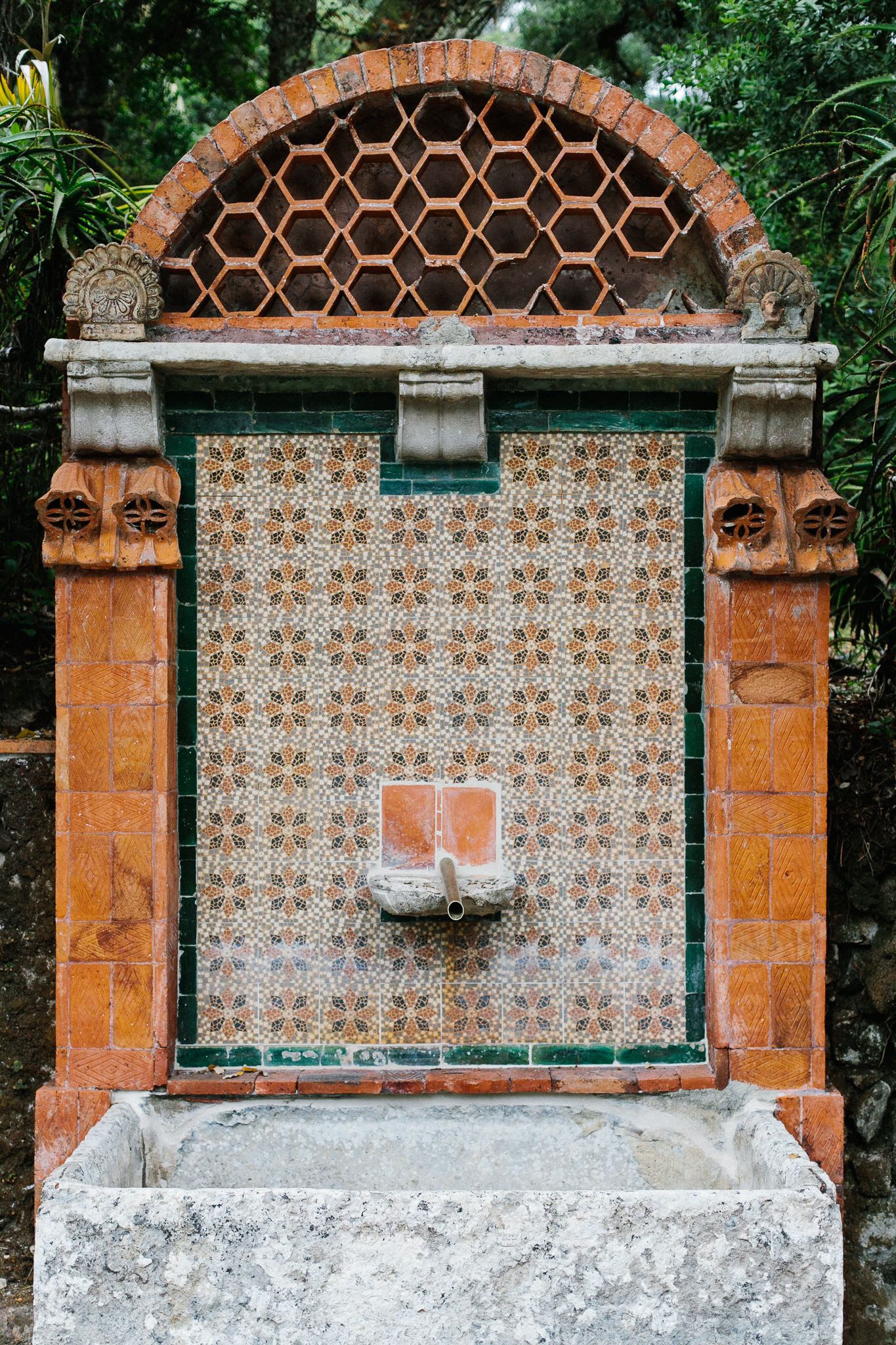 Ornate vintage fountain with decorative tiles and honeycomb pattern arch.