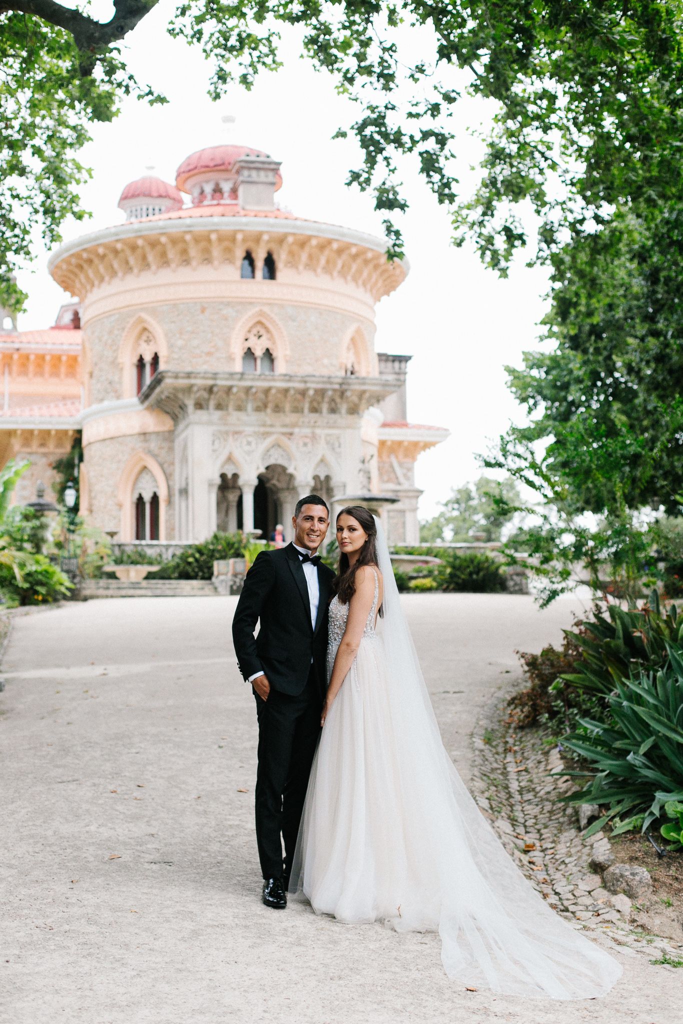 Elegant wedding couple poses before majestic Monserrate Palace architecture.