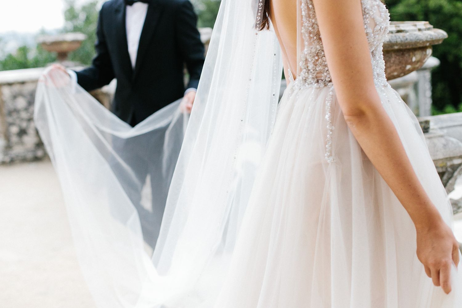 Flowing white wedding veil and dress details captured in soft natural light.